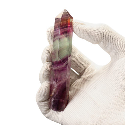Hand holding a multicolored crystal against a white background